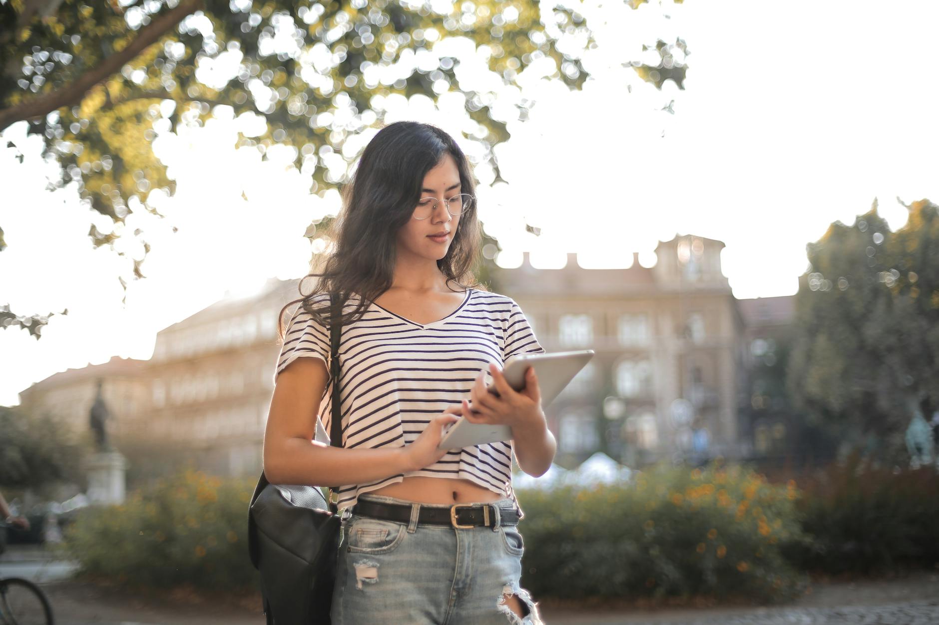 woman in black and white striped shirt and blue denim jeans holding tablet