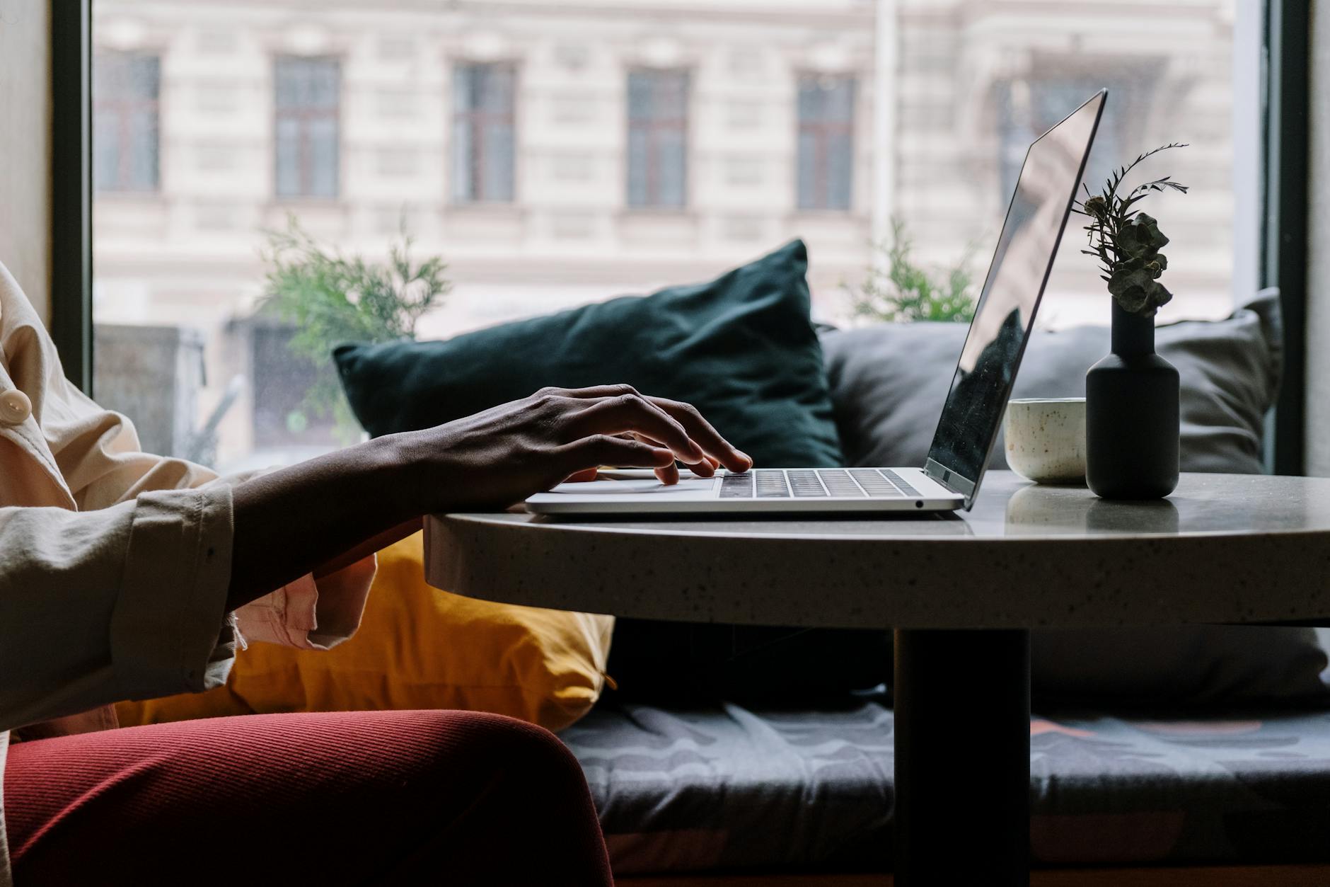 person in red pants sitting on couch using macbook