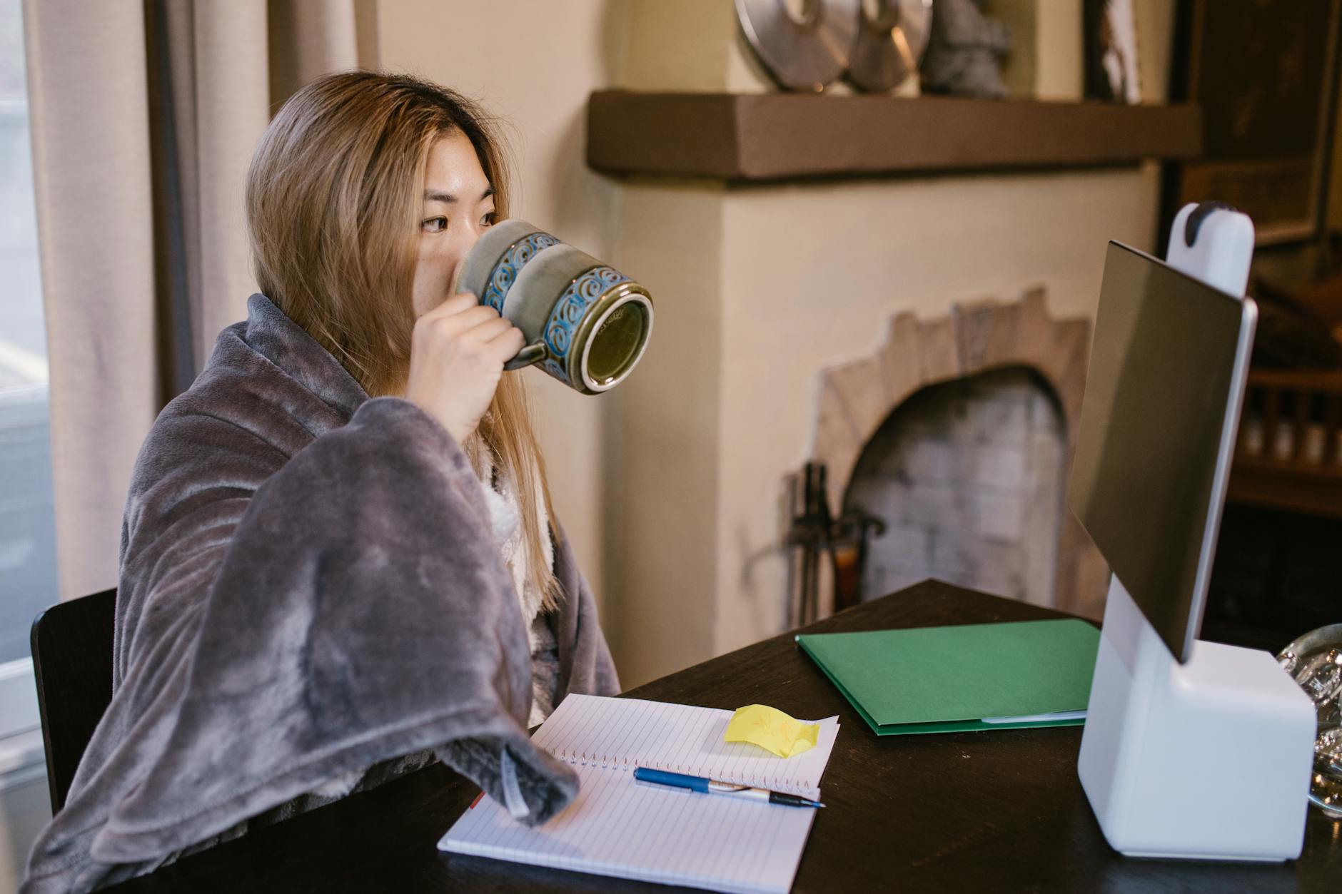 woman in blue denim jacket drinking from white ceramic mug