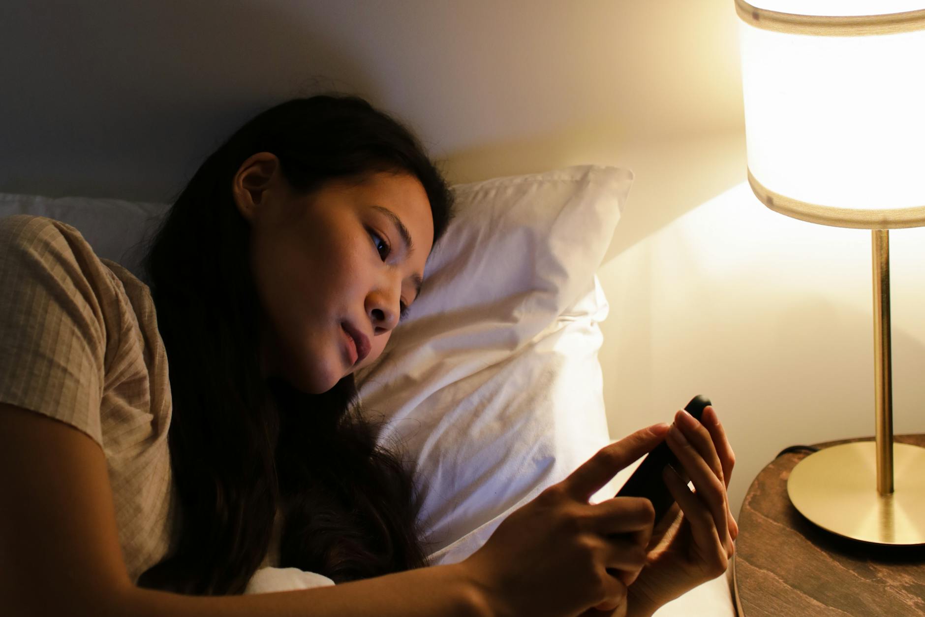 a woman lying on the bed while using her mobile phone